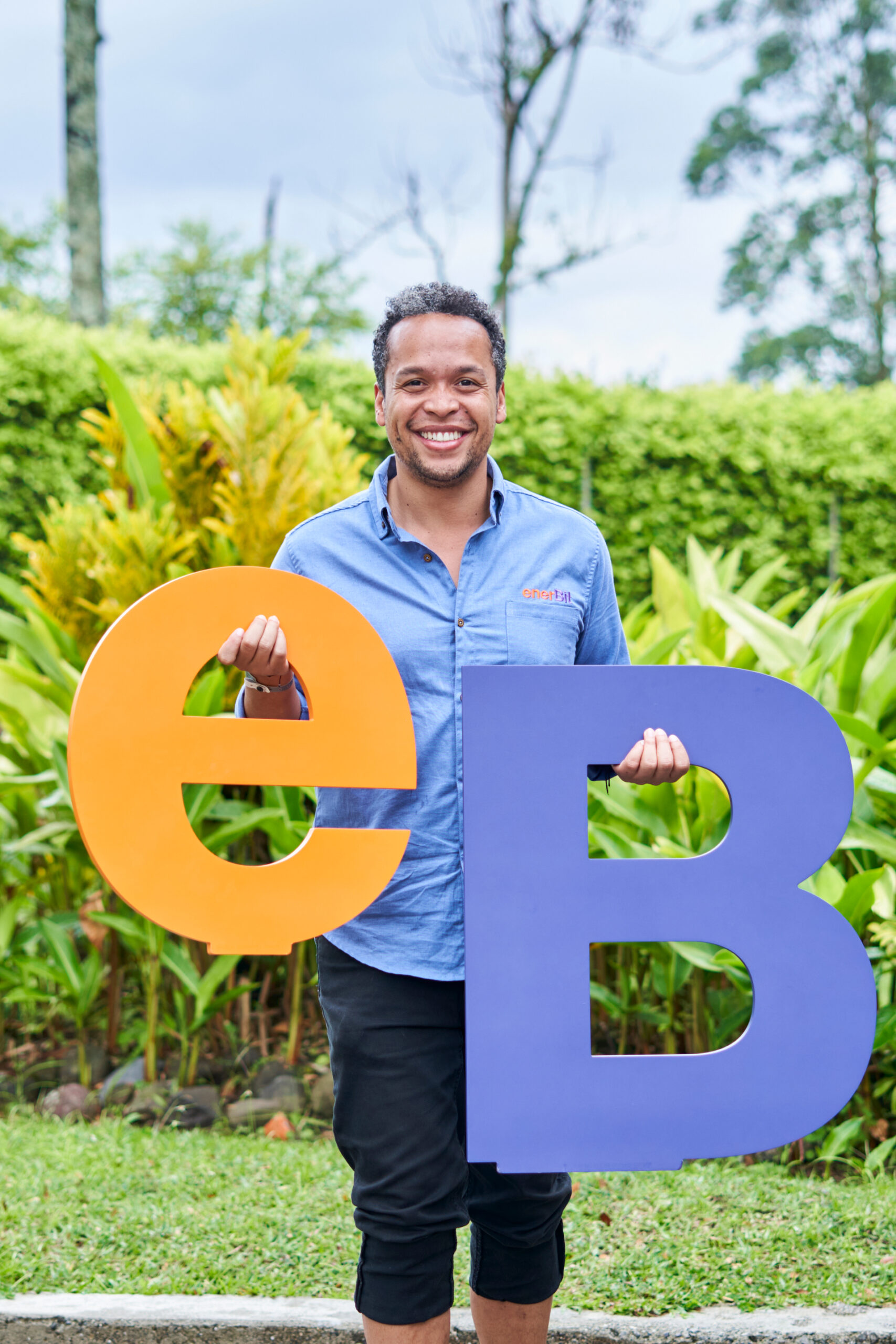 Gabriel Andrés Vizcaino Sánchez líder de enerBit sonriendo a cámara con el isotipo de enerBit gigante